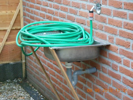 Nieuwe buiten kraan en wasbak opgehangen aan de achterkant 